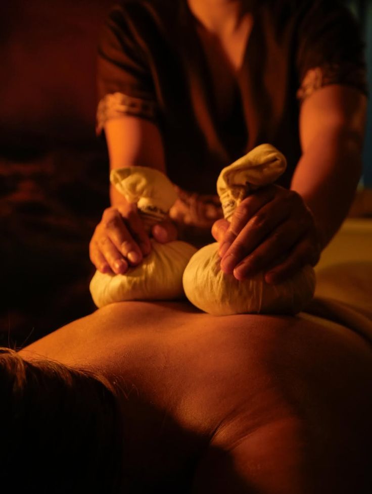 Massage aux pochons d’herbes thaï chauds dans une ambiance tamisée